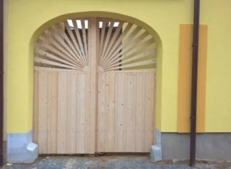 Vrata s vějířem přesně vepsaným do klenby průjezdu ve žlutě omítaném domě.