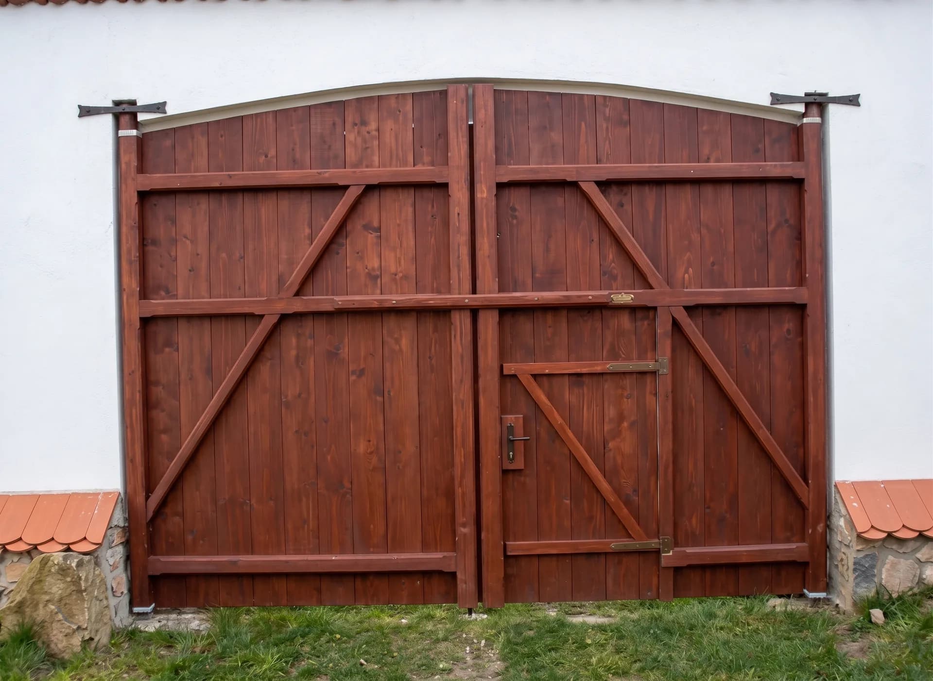 Dvoukřídlá vrata s diagonálními vzpěrami a oblým horním okrajem, v syté hnědé lazuře.